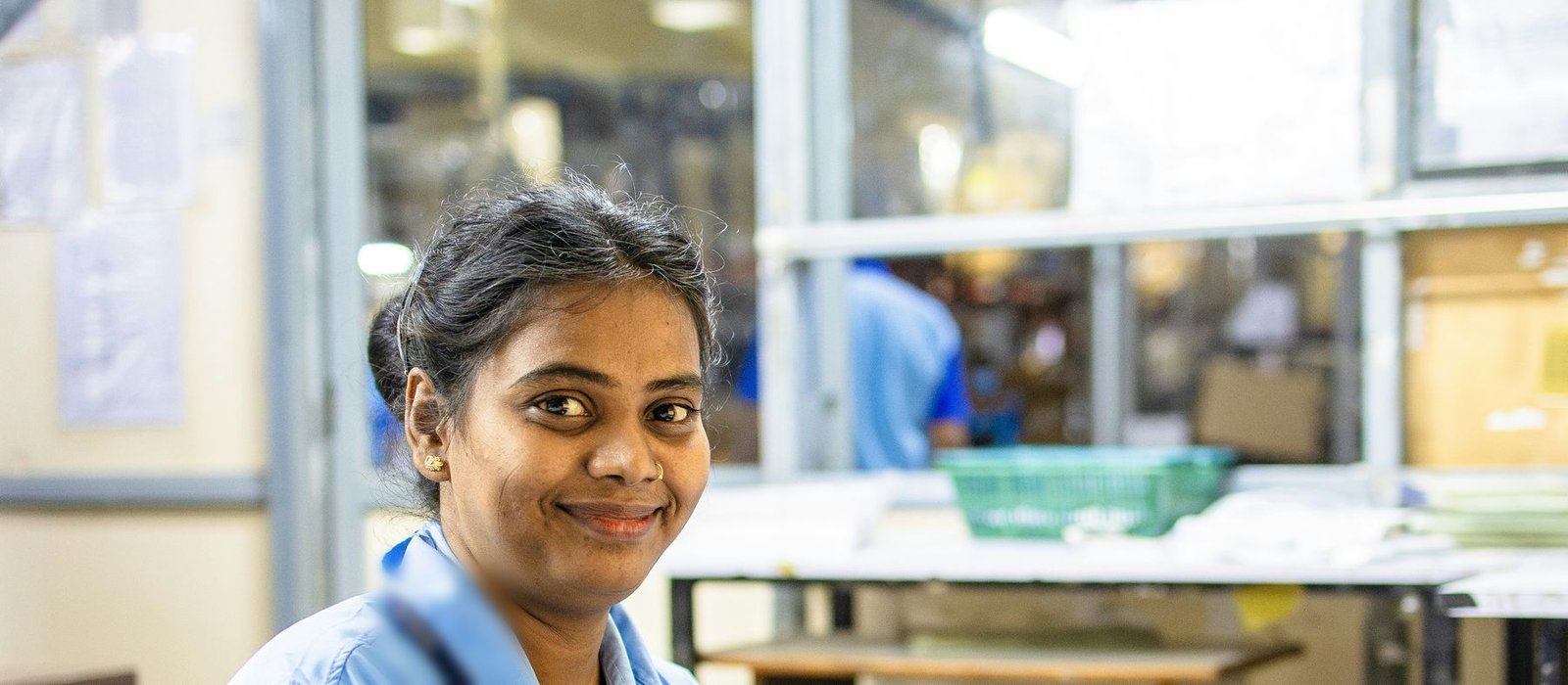 A billing specialist smiling at her desk in a busy back office