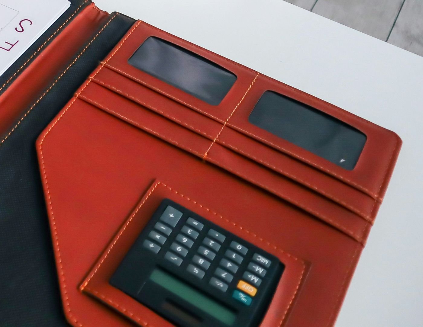 A calculator in an open leather folder on a desk