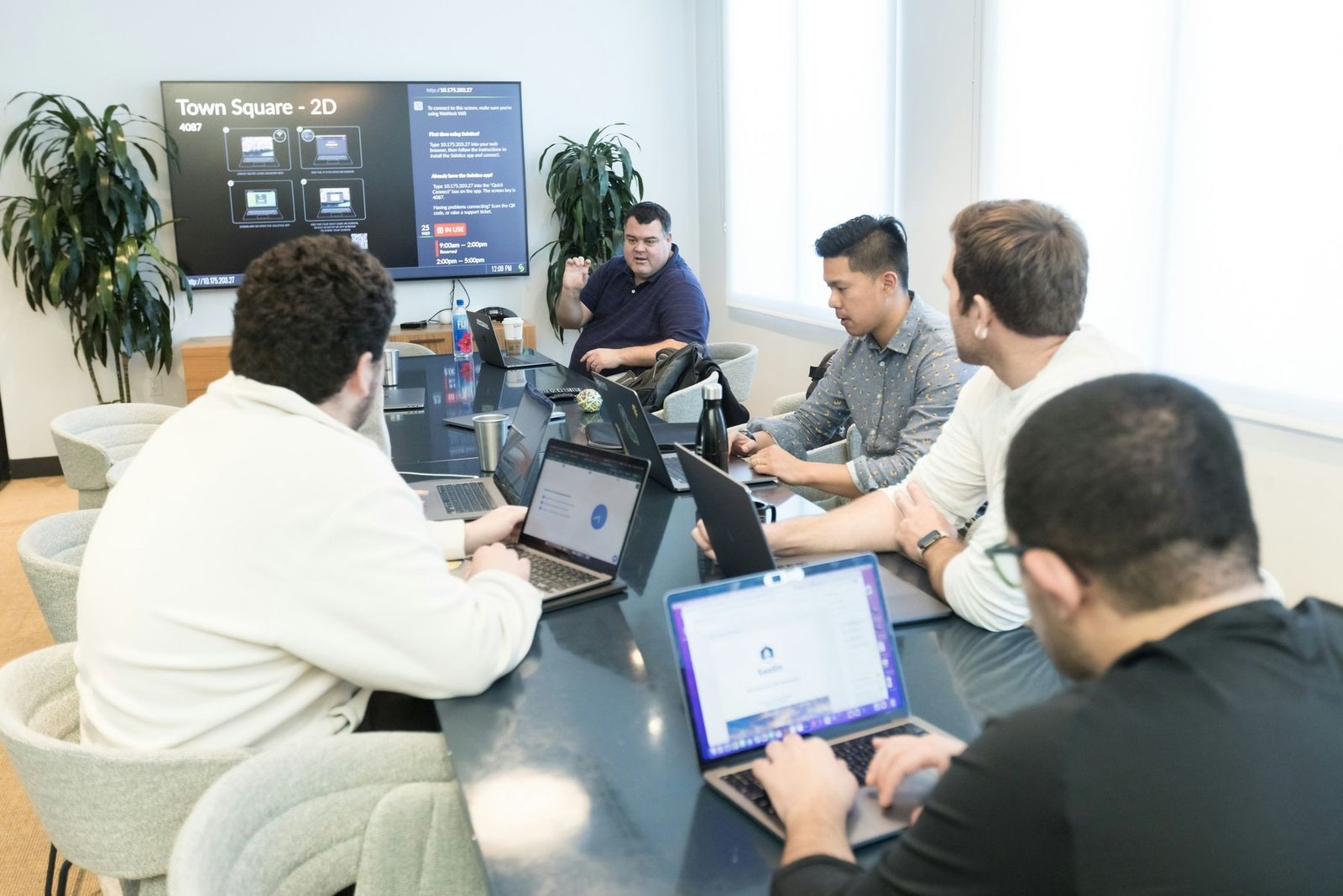 A team working on laptops around a meeting table